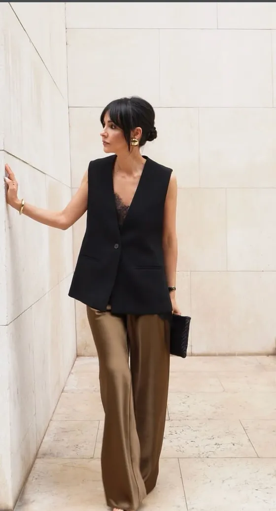Look feminino: colete preto sem mangas sobre calça acetinada em tom bronze