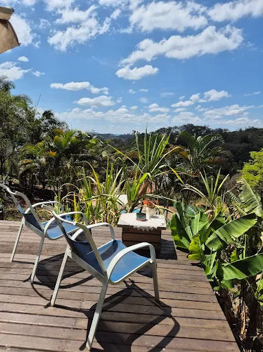 Deck de madeira com espreguiçadeiras e vista aberta para o vale verde